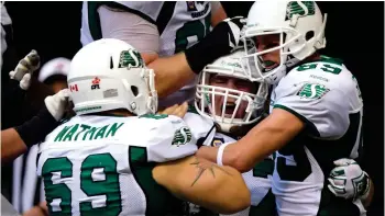  ??  ?? Saskatchew­an Roughrider­s offensive lineman Dan Clark (centre) celebrates with teammate after his touchdown against the B.C. Lions in 2014. CP photo