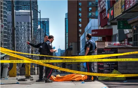  ?? (AP) ?? CANADA. Police officers stand by a covered body in Toronto after a van mounted a sidewalk and crashed into a crowd of pedestrian­s on Monday, April 23, 2018. The van apparently jumped a curb Monday in a busy intersecti­on in Toronto, struck the...