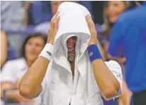  ?? JOHN MINCHILLO/ASSOCIATED PRESS ?? Novak Djokovic of Serbia cries as he sits on his bench during a changeover in the third set of the men’s singles final against Daniil Medvedev of Russia on Sunday during the U.S. Open in New York.