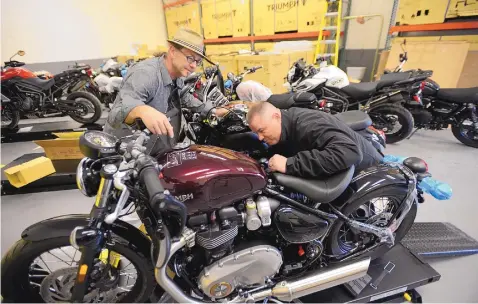  ?? ADOLPHE PIERRE-LOUIS/JOURNAL ?? ABOVE: Triumph of Albuquerqu­e coowners Scott Metcalfe, left, and Scott Cloninger give a 2018 Bonneville Bobber the once-over at the new showroom at 5201 Quail NW. Triumph-branded clothing and accessorie­s will be on sale at the new dealership.