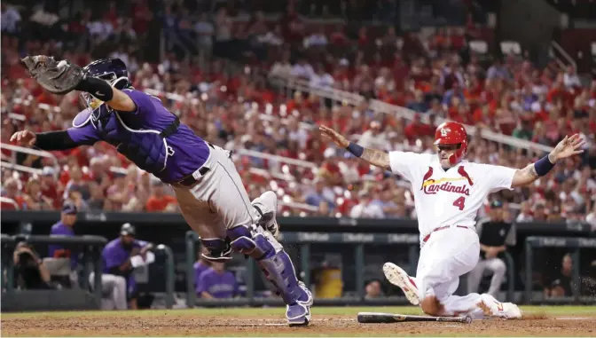  ?? — AP ?? ST LOUIS: Colorado Rockies catcher Tony Wolters, left, dives for the throw from Rockies’ Mark Reynolds as St Louis Cardinals’ Yadier Molina, right, scores during the eighth inning of a baseball game Monday, in St Louis. Reynolds was charged with a...