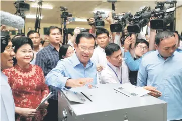  ??  ?? Hun Sen casts his vote as his wife Bun Rany stands beside him at a polling station in Takhmao, Kandal province. — Reuters photo