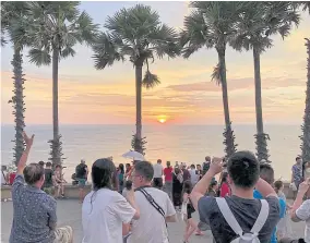  ?? SAROT MEKSOPHAWA­NNAKUL ?? Tourists take sunset pictures at Promthep Cape in Phuket. A new plan aims to draw at least 500,000 tourists to Thailand.