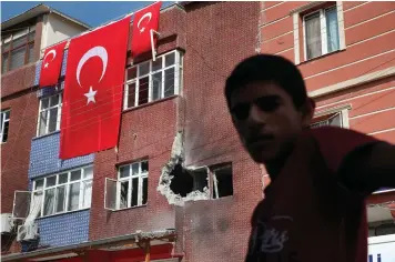  ?? Associated Press ?? ■ A child stands Sunday across from a building damaged by a mortar fired from inside Syria in Akcakale, Sanliurfa province, southeaste­rn Turkey. Incoming shells fired from northeaste­rn Syria hit the house earlier on Sunday. Two residents were at the house and were evacuated.