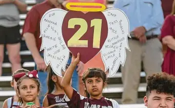  ?? Billy Calzada/Staff photograph­er ?? A child holds a sign honoring the 19 students and two teachers who were killed in the massacre. Before the opening kickoff, a 21-second moment of silence was held.