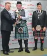  ??  ?? Steven receives his trophy from Nigel Hogden of Andante drums, as George Ussher, president of the Royal Scottish Pipe Band Associatio­n, looks on.