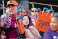  ?? TIM COOK/THE DAY, FILE ?? Cody Garvie waves his Connecticu­t Tigers foam paws June 22, 2019, while sitting on the lap of family friend Dylan McMahon as the Connecticu­t Tigers take on the Lowell Spinners at Dodd Stadium in Norwich.