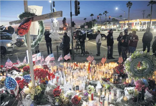  ??  ?? CRIME SCENE: People gather around a makeshift memorial outside the Inland Regional Center where 14 people were killed.