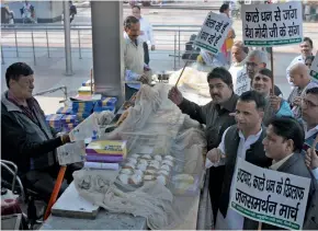  ?? — BIPLAB BANERJEE ?? People (left) stand in a long queue outside an ATM while BJP workers take out a rally in support of cashless transactio­ns in New Delhi on Monday. Fights erupted in queues outside ATMs on Monday as people scrambled for cash. In ITO, two groups clashed...