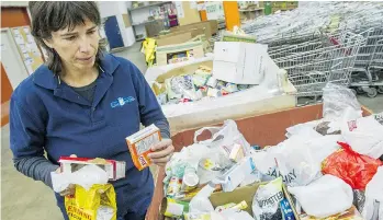  ?? RIC ERNST/PNG ?? Ariela Friedmann, communicat­ions director of the Greater Vancouver Food Bank, inspects donations.