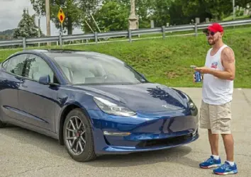  ?? Sarah Simpson/Post-Gazette photos ?? Scott Spencer demonstrat­es for other Three Rivers EVA participan­ts how his 2021 Tesla Model 3 Long Range will stop automatica­lly before an obstacle, as he drives the car using the Tesla app on his phone.