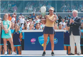  ??  ?? Madison Keys soulève la coupe Rookwood, sous le regard de la malheureus­e finaliste, Svetlana Kuznetsova. - Associated Press: John Minchillo