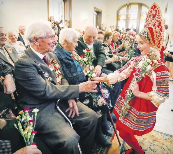  ?? PHOTOS: JOHN MAHONEY ?? Veteran Lazar Chukhovich, 91, is given flowers by Victoria Kuzmina during the ceremony at the Russian consulate.