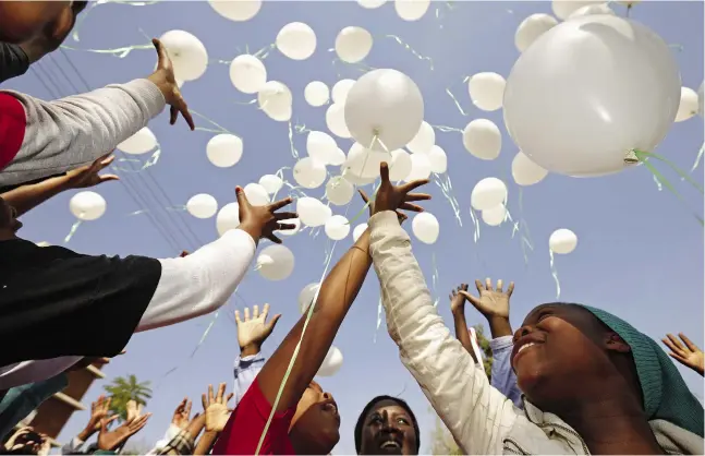  ?? CHIP SOMODEVILL­A / GETTY IMAGES ?? Ninety-five children release 95 balloons Thursday in Pretoria, South Africa, after praying for former president Nelson Mandela outside the Mediclinic
Heart Hospital, where the legendary figure is being treated for a recurring lung infection. Mandela...