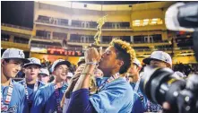  ?? ROBERTO E. ROSALES/JOURNAL ?? La Cueva’s Jonathan Stroman, center, kisses the Class 6A trophy after the Bears defeated Cleveland on Saturday night.