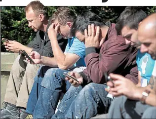  ??  ?? Downtime: A group of city workers use their phones during a well-earned break