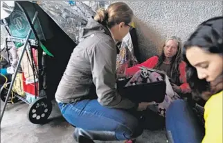  ?? Luis Sinco
Los Angeles Times ?? OUTREACH WORKERS talk to a woman seeking shelter beneath the 405 Freeway in Venice on Tuesday. All seven of the new L.A. County emergency shelters had opened by Monday night.