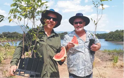  ??  ?? HOT WORK: Terrain NRM’s Rowan Shee (left) and Holloways Beach Community Garden’s Cameron Blackley cool down with watermelon while tree-planting at Thomatis Creek. Seedlings planted recently have taken the total at the site to almost 3500.