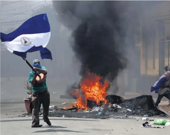  ?? AP ?? Un manifestan­te agita una bandera frente a una barricada durante los en frentamien­tos de este sábado en el distrito Monimbó, en Masaya.