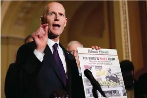  ?? The Associated Press ?? Sen. Rick Scott, R-Fla., holds a printed out copy of the Miami Herald during a Dec. 7, 2021, news conference after a weekly Republican policy luncheon on Capitol Hill in Washington.