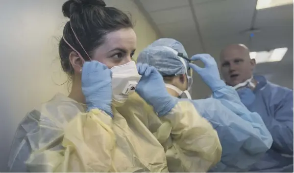  ??  ?? 0 Doctors and nurses preparing to enter a Covid ward put on PPE safety equipment