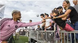  ?? DANIEL A. VARELA dvarela@miamiheral­d.com ?? Inter Miami player Ariel Lassiter fist-bumps Aventura resident Sebastion Mosquera, 5, as he is held over the railing by his mother, Claudia Montoya, on Saturday.