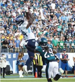  ?? GETTY IMAGES ?? Corey Davis of the Titans corrals the winning touchdown pass in overtime, despite the defensive efforts of the Eagles’ Avonte Maddox.