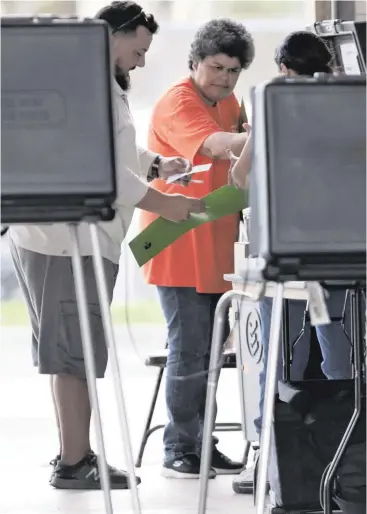  ?? CARL JUSTE cjuste@miamiheral­d.com ?? Voters cast ballots Tuesday with the help of poll workers at the Hialeah Fire Station #5 during the Florida primary.