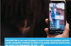  ?? — AFP ?? PHILADELPH­IA: A man uses his phone to record former vice president and Democratic presidenti­al candidate Joe Biden as he speaks about the unrest across the country from Philadelph­ia City Hall.