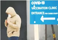  ?? RYAN REMIORZ / THE CANADIAN PRESS ?? A man walks past a vaccinatio­n site in Quebec, which
announced it will wait 90 days between doses.