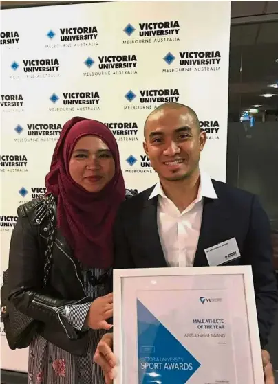  ??  ?? That’s my man: Track cyclist Azizulhasn­i Awang and wife Athiah Ilyana Abd Samat posing with his best male athlete award at Victoria University in Melbourne on Thursday.