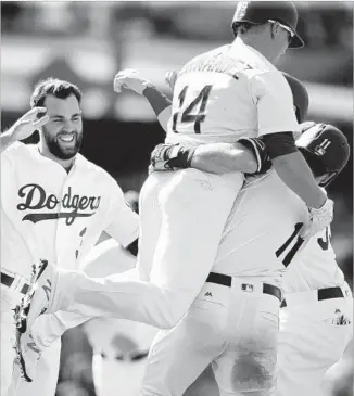  ?? Alex Gallardo Associated Press ?? LOGAN FORSYTHE (11) celebrates with Enrique Hernandez (14) and Chris Taylor after delivering the game-winning hit in the 10th inning to lift the Dodgers over the Atlanta Braves 5-4.