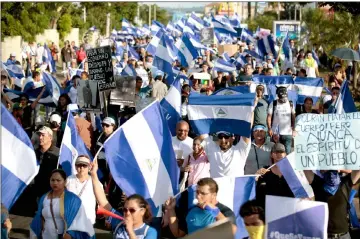  ??  ?? People taking part in a march marking a month since the beginning of protests against the government in Managua. — AFP photo