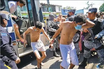  ?? Marvin Recinos AFP/Getty Images ?? MEN apprehende­d on suspicion of links to gangs are escorted in San Salvador in March. Authoritie­s have imprisoned more than 35,000 people whom President Nayib Bukele describes as “terrorist” gang members.