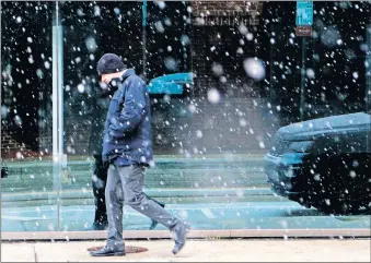  ??  ?? A man walks through snowfall on Robinson Avenue as snow falls in downtown Oklahoma City on Tuesday. [DOUG HOKE/THE OKLAHOMAN]