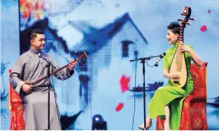  ??  ?? Gao Bowen (left) is performing pingtan on stage in a traditiona­l Chinese long gown.