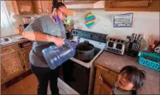  ??  ?? Amanda Larson who has no running water at her home, carries water for her son Gary Jr to have a bath in the Covid-19 virus affected Navajo Nation town of Thoreau in New Mexico on May 22.