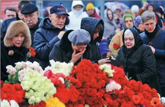  ?? REN QI / CHINA DAILY ?? Top: Residents lay flowers and mourn victims of Friday night’s terror attack outside the Crocus City Hall concert venue near Moscow, Russia, on Sunday.