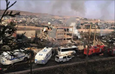  ?? DHA VIA AP ?? Smoke still rises from the scene after Kurdish militants attacked a police checkpoint in Cizre, southeast Turkey, Friday with an explosives-laden truck, killing several police officers and wounding dozens more, according to reports from the state-run...