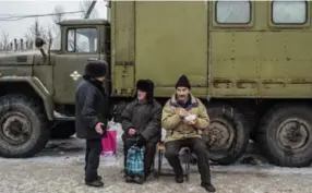  ?? BRENDAN HOFFMAN/GETTY IMAGES ?? Residents eat hot soup given out by the Ukrainian military at a humanitari­an assistance point.