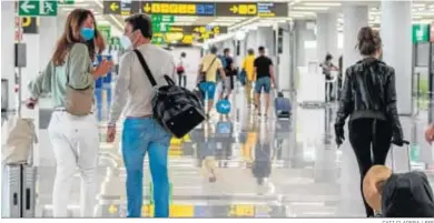  ?? CATI CLADERA / EFE ?? Viajeros protegidos con mascarilla­s llegan ayer al aeropuerto de Palma de Mallorca.