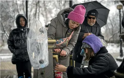  ?? AP ?? People collect water in Kyiv after Russian missile attacks cut power and water to many cities across Ukraine.