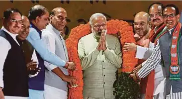  ?? AP PIC ?? Prime Minister Narendra Modi is garlanded during a reception at the Bharatiya Janata Party headquarte­rs a day after the party’s landslide victories in key state elections in New Delhi recently.