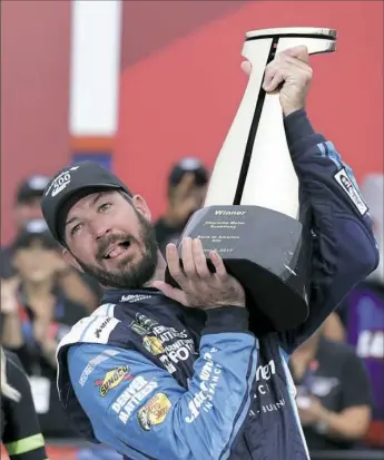  ?? Chuck Burton/Associated Press ?? Martin Truex Jr struggles to raise the trophy in Victory Lane after winning Sunday at Charlotte Motor Speedway. It was his sixth victory of the season.