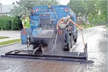  ?? JOHN KLEIN, MILWAUKEE JOURNAL SENTINEL ?? Workers apply slurry seal in August 2011 on a street in Milwaukee’s south side. Older streets are sealed with this quick-setting method to extend the life of the pavement.