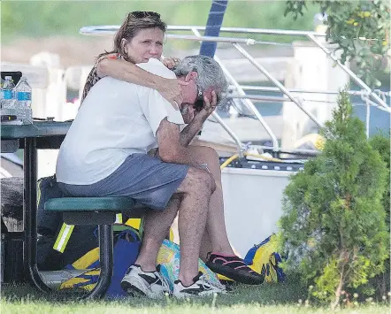  ?? DAX MELMER ?? Two people, believed to be occupants of the boat when a woman went missing in Lake Erie, console each other at Colchester Harbour marina on Sunday. The woman began to struggle while swimming before going under, the OPP said.