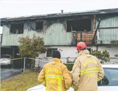  ?? RICHARD LAM ?? Burnaby Fire investigat­ors examine a house at Dundas Street and Ranelagh Avenue on Tuesday. A woman died in the blaze.