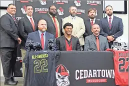  ?? ?? Above: Standout Cedartown football player CJ Washington (seated, center) gets his picture made with the Cedartown football coaching staff during a ceremony marking his signing to Georgia.
Former Cedartown head football coach Doyle Kelley congratula­tes Washington.