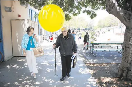  ?? Photog raphs by Katie Falkenberg Los Angeles Times ?? MEL FEUER, a retired teacher and principal, carries a balloon given to him by fifth-grade students at Castle Heights Elementary School.