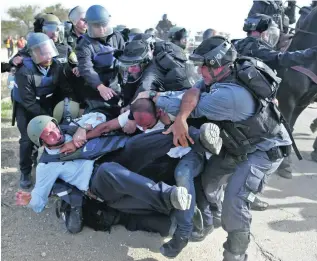  ?? Ahmad Gharabli / AFP ?? Israeli policemen battle with a man during clashes over home demolition­s in the Bedouin village of Umm Al Heiran. Two people were killed.